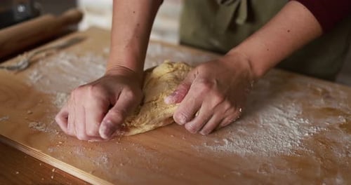 Close Up of Hands Kneading Dough on a Floured Wooden Board