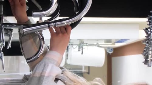A Woman Examines the Assortment in a Plumbing Store Buying Sanitary Ware in a Hardware Supermarket