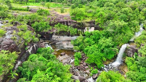 Aerial view of lush tropical waterfall surrounded by dense jungle.