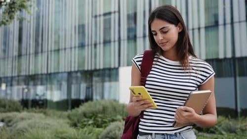 Young Hispanic Woman Using Mobile Phone in Business Office District in Modern City Student