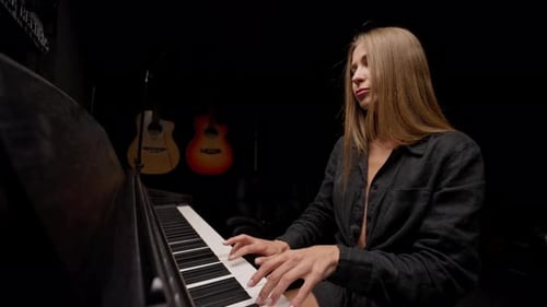 Female pianist preparing for a concert and playing a lyrical melody on the piano keys in studio