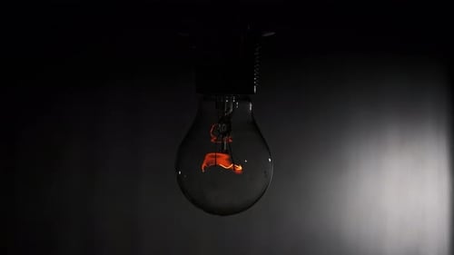 L'ampoule à incandescence s'allume et s'éteint et scintille sur fond noir