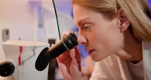 In Bright Medical Science Laboratory Beautiful Microbiologist Looks Under