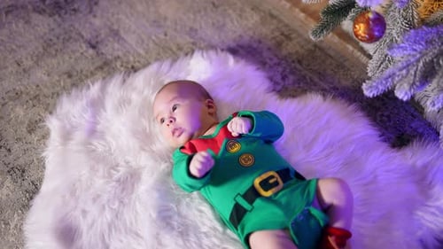 Adorable Infant Wearing Elf Costume by Christmas Tree