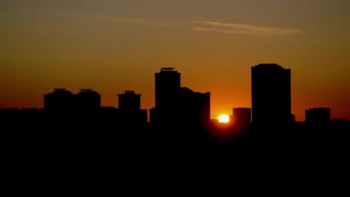 Silhouetten von Hochhäusern im Zeitraffer bei Sonnenuntergang. Orangefarbener Sonnenuntergang im Stadtbild
.