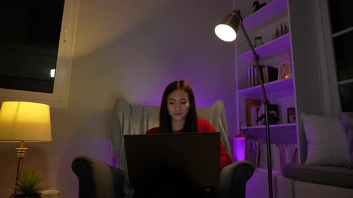 Asian woman working late at night with laptop computer home office looking screen monitor