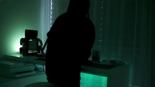 une hackergirl criminelle à capuche noire utilisant un ordinateur portable et de gros ordinateurs pour pirater son système réseau