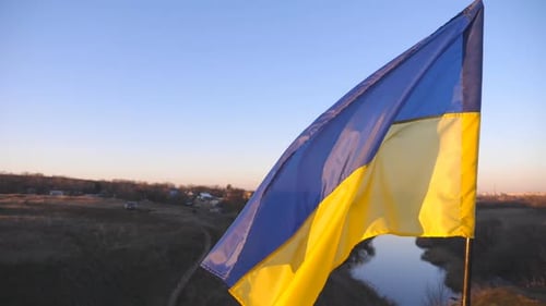 Ukrainian Flag Waving on a Pole at Sunset