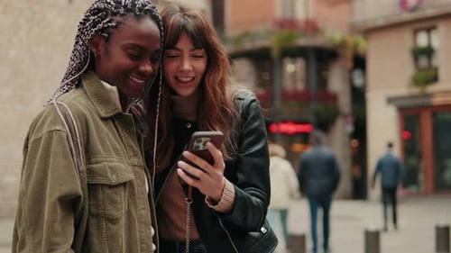 Two Friends Looking at Phone in City