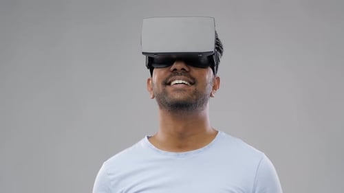 Man experiencing virtual reality with headset on gray background