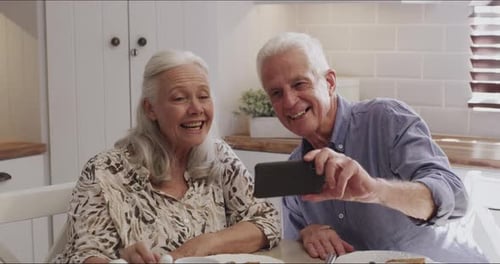 Senior Couple Taking Selfie Together at Table
