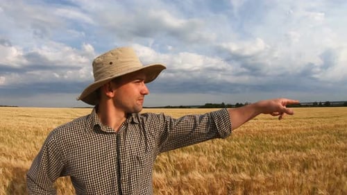 Male Farmer Standing on Barley Meadow and Looking at Cereal Plantation