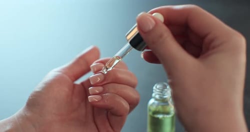 Woman applying cuticle oil to her fingernails