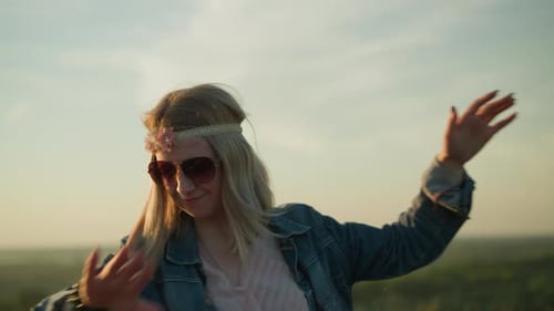 Carefree Woman Dancing with Joy in Sunglasses and Floral Headband