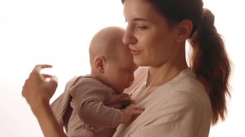 At Home Young Happy Mother is Keeping in Arms and Caressing Newborn Baby Smiling Standing in