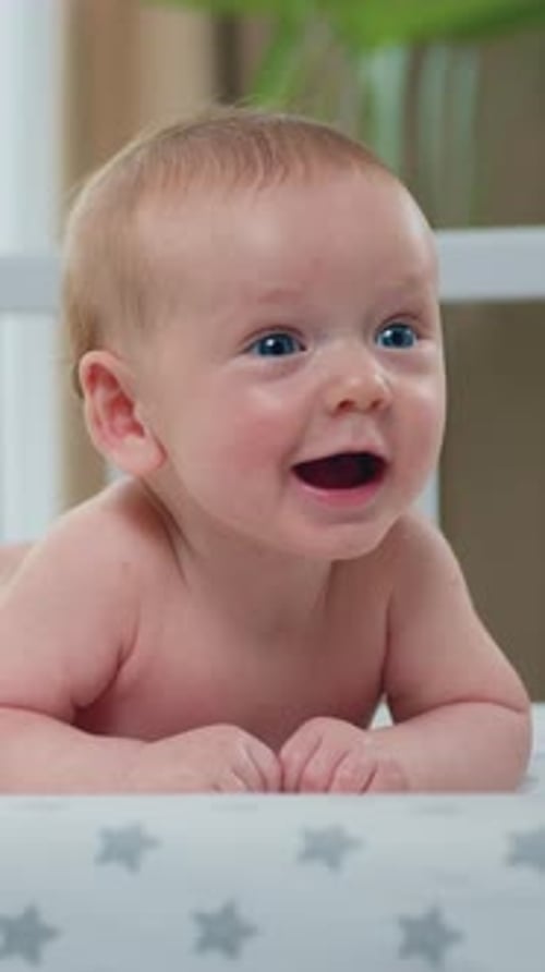 Adorable baby smiling and lying on stomach in crib