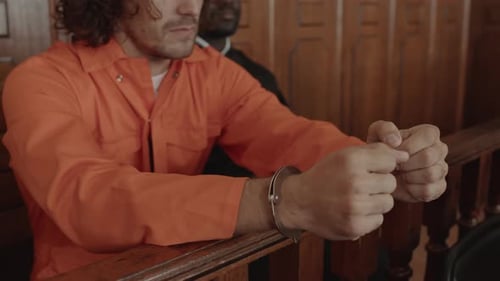 Hands of Young Male Suspect in Metallic Cuffs Wearing Orange Jumpsuit