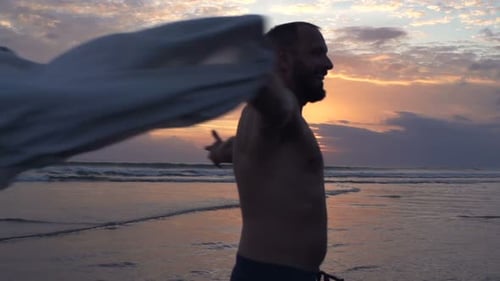 Homem se virando na praia durante o pôr do sol