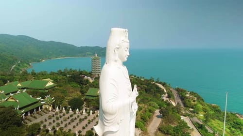 White Marble Statue Standing Tall Overlooking Verdant Rooftops of Linh Ung Pagoda and Turquoise Gulf