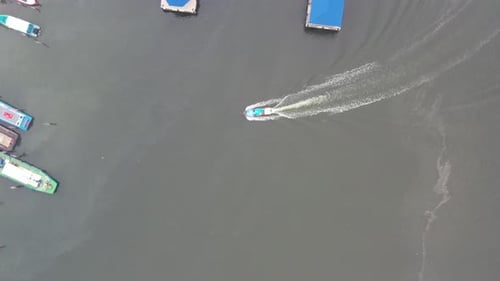 Aerial vertical top down view of a small traditional fishing boat returning to the shore after a mor