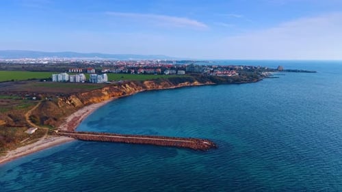 Scenery of the coastal city from drone footage. Rising at the dam cutting into the blue waterscape.
