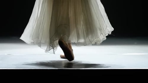 Graceful Ballerina in a White Tutu Balancing in Pointe Shoes View of the Legs Dark Background