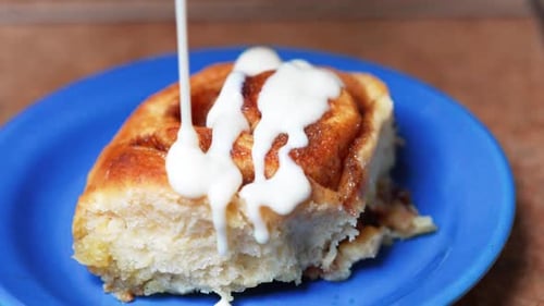 Drizzling icing on a homemade cinnamon roll - isolated close up
