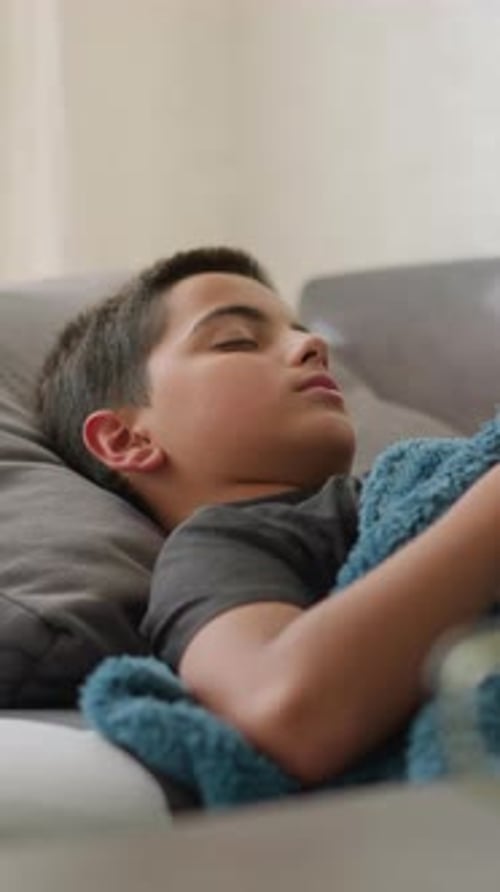 Sick Kid Resting on Couch Coughing with Tissue Nearby and Cup on Table