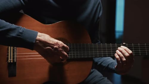 Person Playing Acoustic Guitar in Close Up