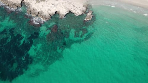 Rocky Shoreline With Crystal-clear Turquoise Water At Sandy Beach On Sunny Day In Spain. aerial shot