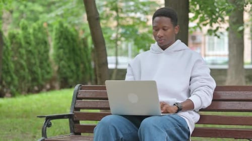 Man Works on Laptop in Green Urban Park