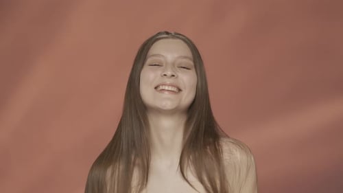 A Woman Demonstrates Silky Healthy and Shiny Long Hair Cheerful Young Woman in the Studio on a Red