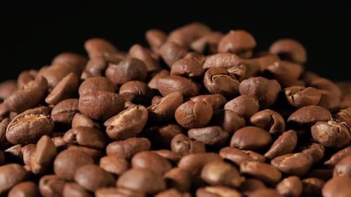 Slow motion of roasted coffee beans falling.