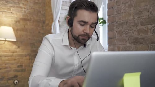 Businessman Using Laptop While Working in a Call Center