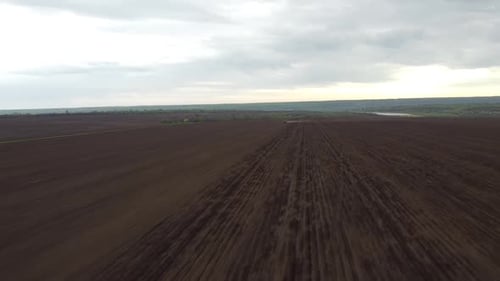 Blue tractor with yellow seeder working on the field in Ukraine OA