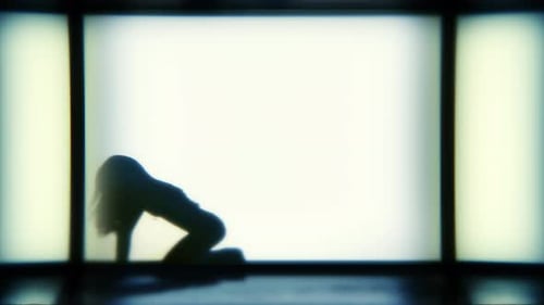 Eine Silhouette-Frau tanzt lässig vor einem hellen Bühnenhintergrund