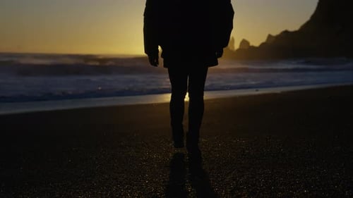 Silhouette Strolls on Black Sand Beach at Sunset