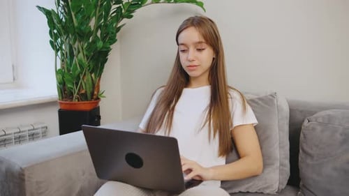 A Young Woman is Engaged in Working on Her Laptop at Home Surrounded By a Cozy and Inviting