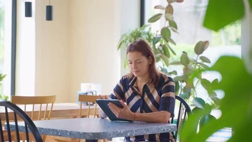 Relaxed Woman Reading Information Browsing Online in Tablet Sitting in Cafe