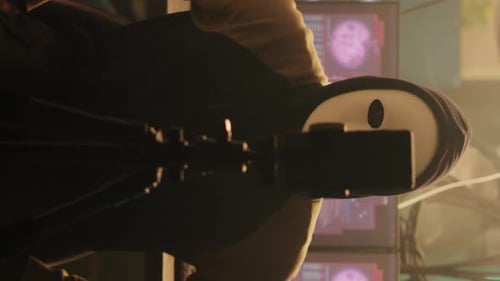 Masked Hacker Uses Phone in Dark Room