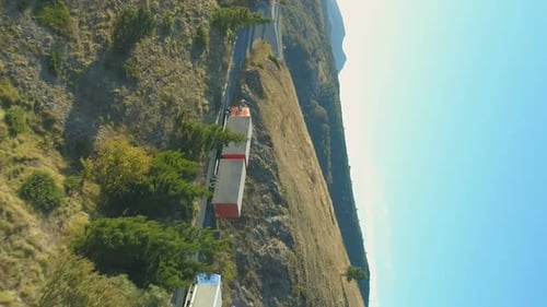 Drone Following Cargo Truck Trailer Driving Up a Winding Road Through Mountain Pass Bulgaria During