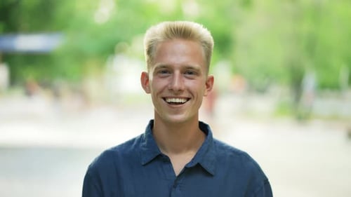 Close Up Portrait Young Happy Blond Man Standing in Nature Between Park Trees Relaxes Breathes Fresh
