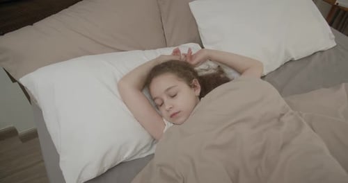 Young Girl Wakes, Yawns, and Stretches in Bed