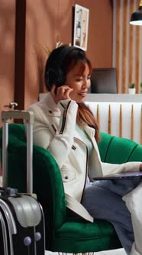 Vertical Video Asian Woman Enjoying Movie on Laptop in Hotel Lounge Area