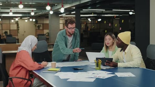 Diverse Team Collaborating on Plans in Open Office