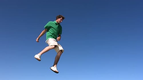 Man Performing Gymnastic Flip in Clear Blue Sky