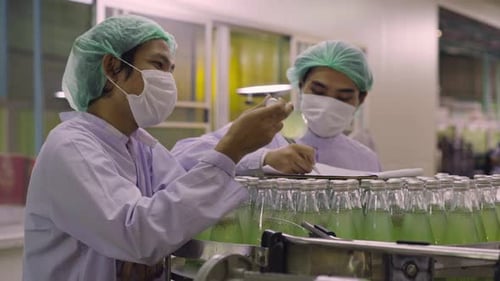 Un ouvrier industriel inspecte sa qualité dans une usine de fabrication de bouteilles de jus