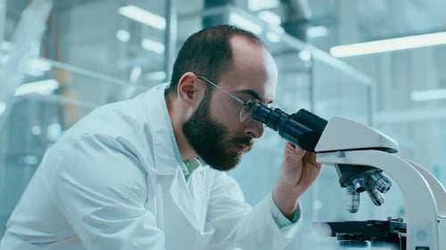 Scientist Looks Through Microscope in Modern Laboratory