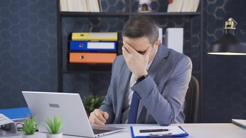 Mature businessman working on laptop alone in office is shocked.