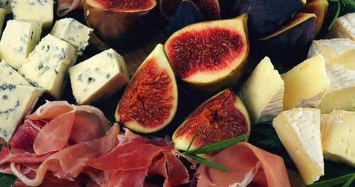 Figues, jamon, feuilles d'épinards et fromages bleus sur une planche de bois. Set de snacks.